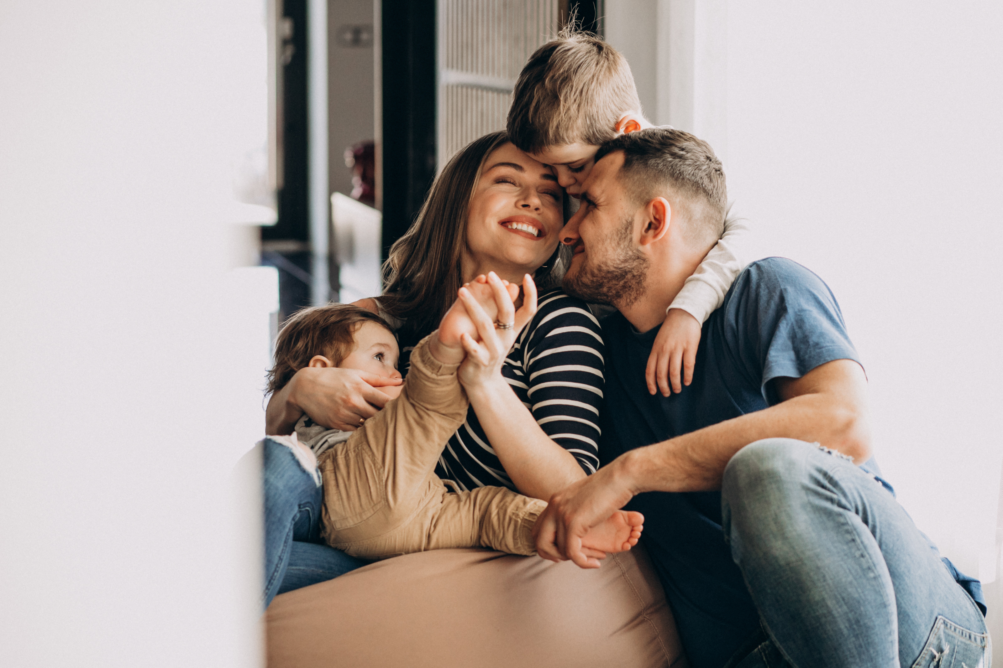 Junge Familie kuschelt lachend auf dem Sofa
