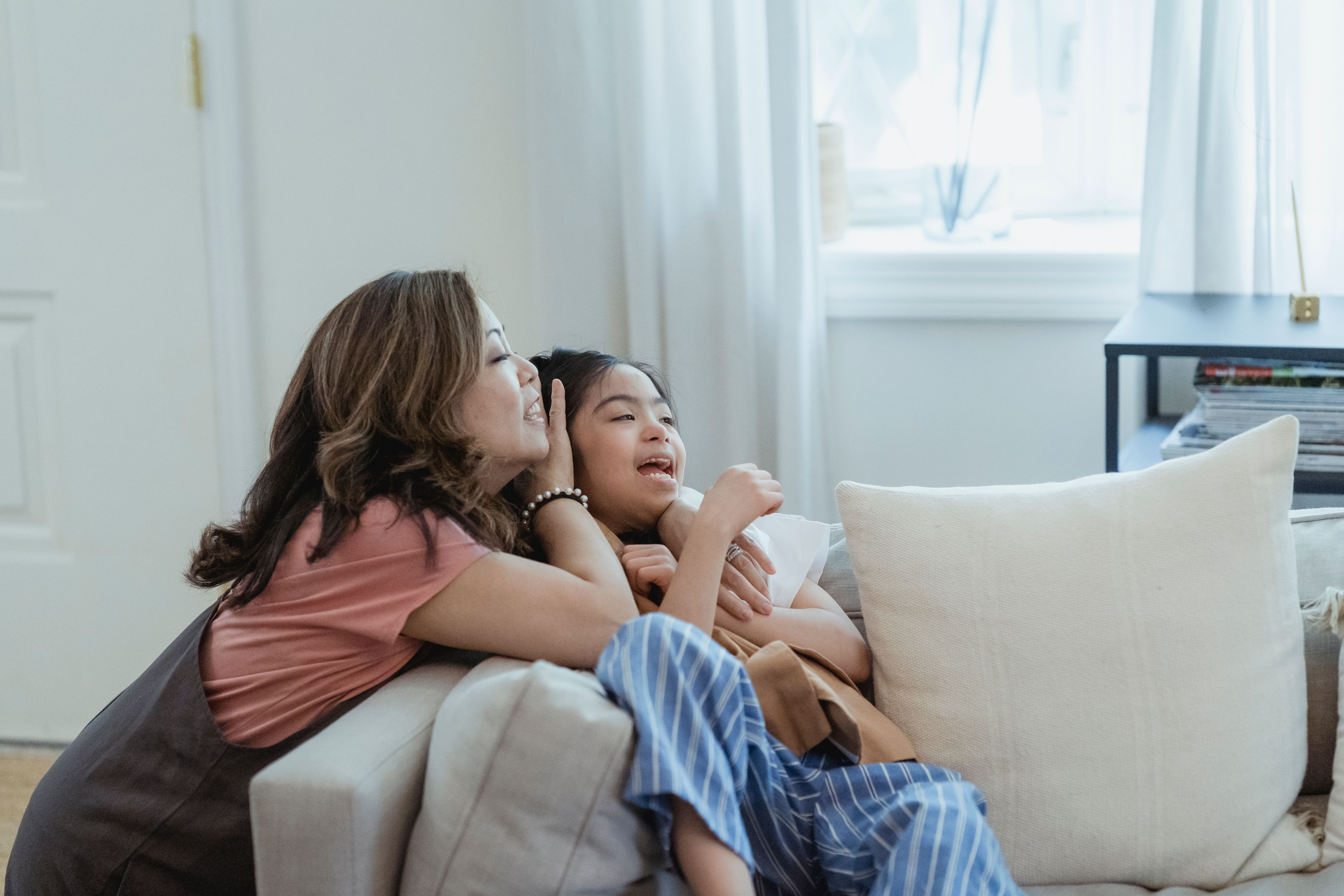 Mutter und Tochter lachen gemeinsam auf einem Sofa